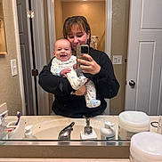 Dean is registered to the contest to win money with this photo: baby, bathroom, casual, child, door, happy, holding, indoor, light, mirror, mirror_selfie, pajamas, person, reflection, selfie, sink, smile, toiletries, woman, young