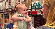 Dean joined the competition — help win amazing prizes! aisle, baby, blond_hair, boxes, clothing, flooring, happy, holding, infant, interaction, joy, person, retail, shelves, shopping, shopping_cart, smiling, store, warehouse, woman