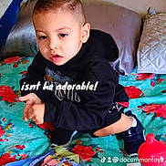 King joined the competition — help win amazing prizes! child, boy, black_hoodie, bed, colorful_bedspread, books, sippy_cup, indoor, cute, face, short_hair, sitting, toy, playful_text, pillow, blanket, floor, clothing, young_child, expression