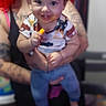 adult, baby, blue_pants, blurred_background, candid, child, clothing, family, happy, holding, human, indoor, messy_face, person, portrait, red_hair, short_sleeve_shirt, smiling, snack, tattoo