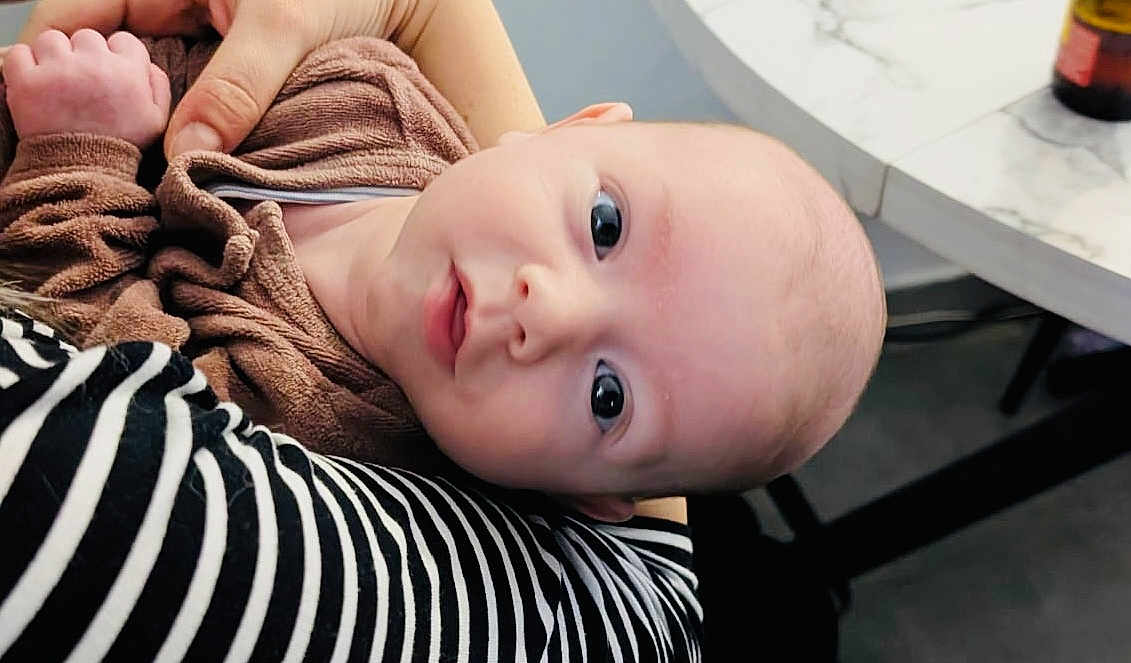 Elio participe au concours pour gagner de l'argent avec cette photo : baby, infant, face, eyes, person, clothing, striped_shirt, hand, marble_table, indoor, curious, holding, young_child, portrait, head, skin, expression, cuteness, closeup, tender_moment