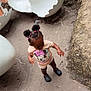 toddler, child, outdoor, concrete, hair_ties, minnie_mouse, clothing, footwear, sculpture, eggshell, playground, curious, standing, nature, rocks, dirt, shorts, black_shoes, pink, braids