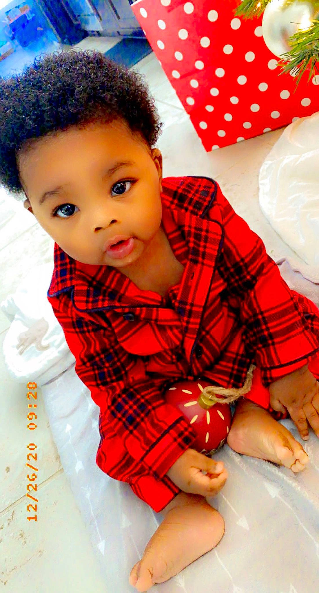 Gregory is registered to the contest to win money with this photo: arm, baby_toddler_clothing, cheek, child, eye, finger, hair, hand, happy, head, lip, pattern, person, pink, plaid, red, skin, sleeve, tartan, textile