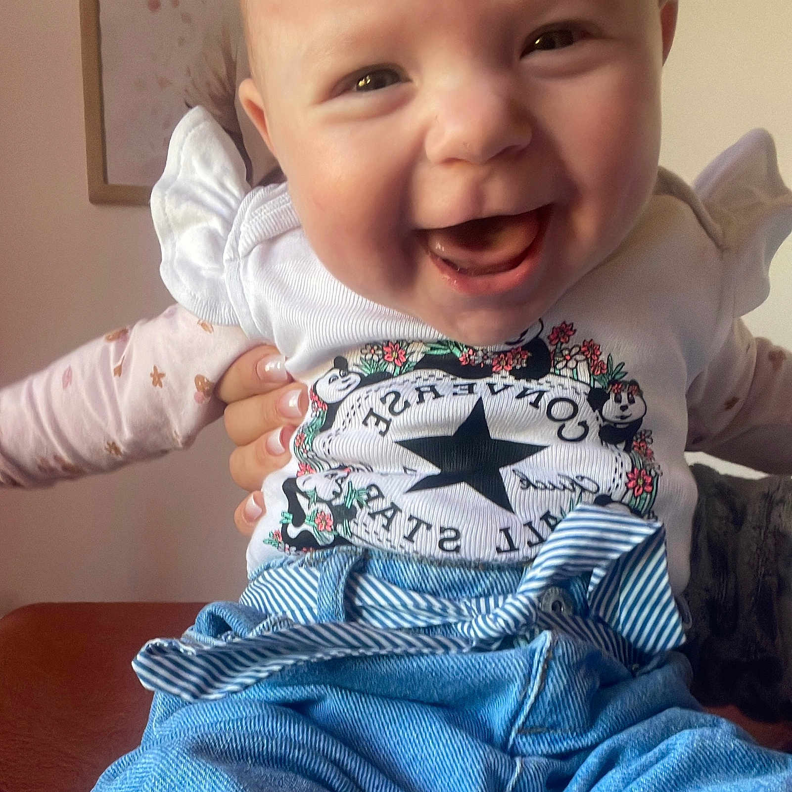 Giulia a rejoint le concours — aidez-le/la à gagner de superbes lots ! baby, child, smiling, happy, clothing, shirt, pants, hand, face, portrait, indoor, person, cute, joyful, blue, white, pattern, furniture, frame, holding