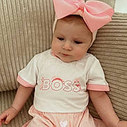 Carmen participe au concours pour gagner de l'argent avec cette photo : baby, child, pink_bow, headband, shirt, boss_text, couch, beige, clothing, infant, cute, portrait, sitting, indoors, soft_lighting, young_child, expression, person, fabric, comfortable
