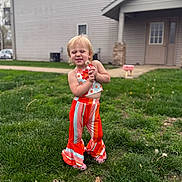 Athena joined the competition — help win amazing prizes! child, toddler, outdoor, grass, house, playful, smile, colorful_clothing, flower_pattern, striped_pants, greenery, young_child, happy, cute, person, daylight, casual, portrait, standing, fun