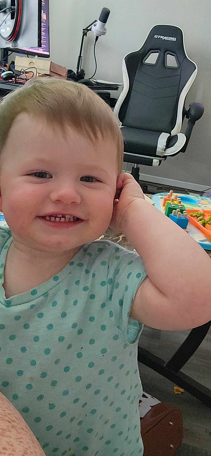 Meradith is registered to the contest to win money with this photo: toddler, child, smile, polka_dot, shirt, indoor, gaming_chair, toy, play_area, table, floor, happy, face, person, cute, hair, skin, expression, room, furniture