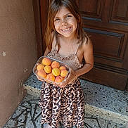Inaya a rejoint le concours — aidez-le/la à gagner de superbes lots ! child, girl, smile, apricots, fruit, glass_container, leopard_print, skirt, shoes, door, wooden_door, floor, stone_floor, patterned_floor, summer, happy, standing, outdoor, portrait, young