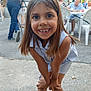 Inaya a rejoint le concours — aidez-le/la à gagner de superbes lots ! adult, butterfly_sandal, casual_clothing, child, concrete_ground, daylight, dress, girl, happy, missing_tooth, outdoor, people, playful, sandals, short_hair, smiling, social_gathering, summer, table, white_chair