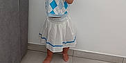 Djèlyssa participe au concours pour gagner de l'argent avec cette photo : toddler, child, barefoot, pointing, smiling, indoor, floor, tile_floor, skirt, top, hair_tied, white_wall, couch, gray_couch, playful, person, young_child, skin, foot, hand