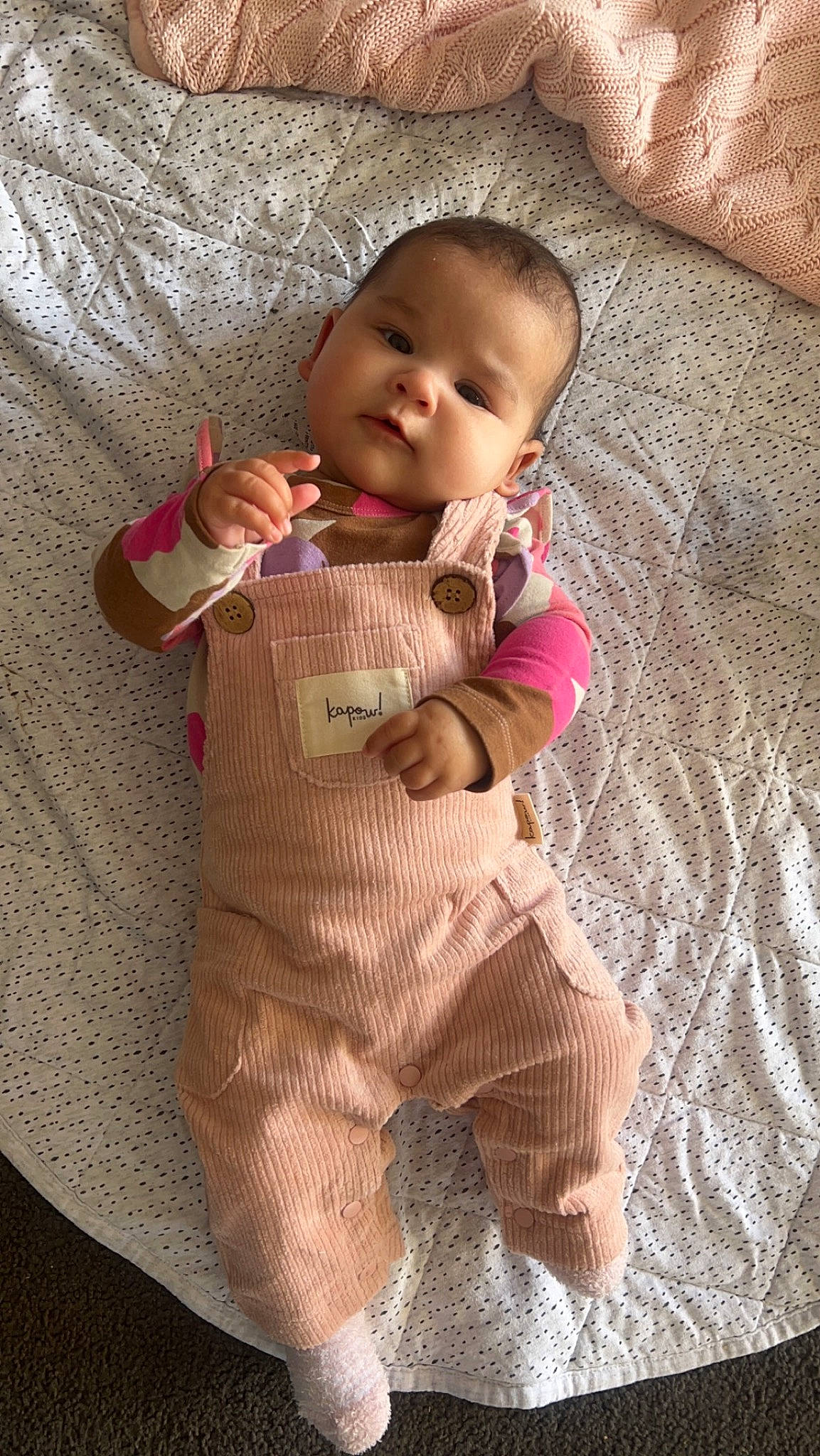 Leni is registered to the contest to win money with this photo: arm, baby, baby_products, baby_toddler_clothing, cheek, child, collar, comfort, face, flooring, head, linens, nose, pattern, person, skin, sleeve, smile, thumb, toddler