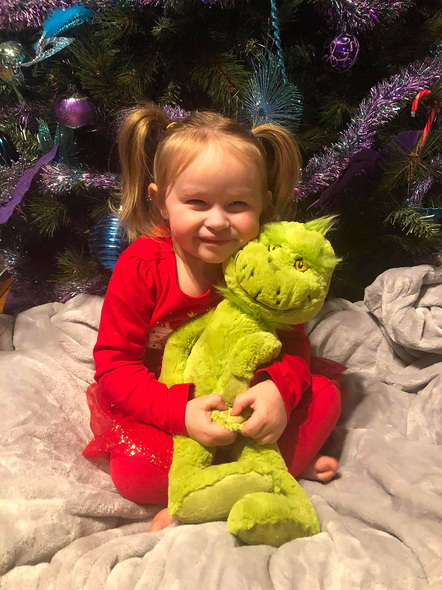 Bethany is registered to the contest to win money with this photo: baby_toddler_clothing, baby_toys, child, christmas, christmas_decoration, christmas_tree, facial_expression, fictional_character, happy, holiday, human, human_body, joy, organ, person, pink, play, plush, stuffed_toy, textile