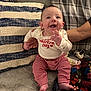 baby, infant, smiling, happy, sitting, clothing, striped_pants, long_sleeve_shirt, valentine_day, pillow, blanket, couch, hand, adult, indoors, cozy, cheerful, face, person, home