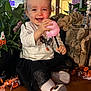 toddler, child, smiling, indoor, halloween, toy, pink, skull, black_skirt, white_shirt, plant, decoration, pumpkin, orange, wood, happy, curly_hair, sitting, festive, holiday