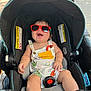 baby, child, stroller, sunglasses, smiling, outdoor, sunny, romper, infant, happy, seatbelt, seat, person, cute, summer, walking, sidewalk, shade, playful, accessory