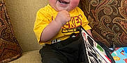 Dallas joined the competition — help win amazing prizes! toddler, child, smiling, curly_hair, yellow_shirt, mickey_mouse, black_pants, sitting, couch, patterned_cushion, book, colorful, happy, indoors, feet, hand, toy, playful, cozy, portrait