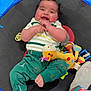 Dallas is registered to the contest to win money with this photo: baby, child, smiling, trampoline, toy, green_pants, striped_shirt, indoor, footwear, sock, colorful, playtime, happy, cute, infant, person, dinosaur_pattern, soft_toy, hand, face