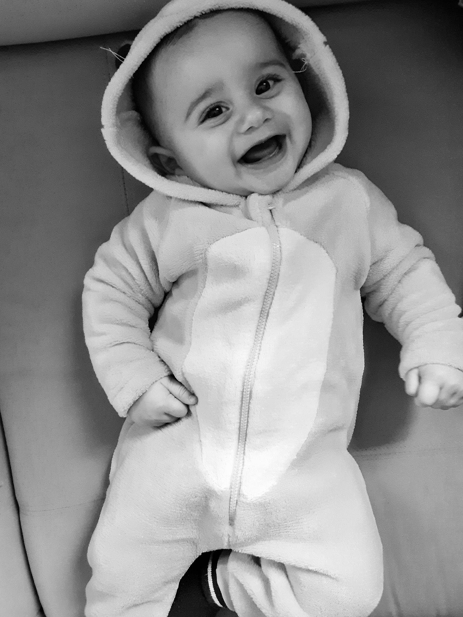 Adam participe au concours pour gagner de l'argent avec cette photo : baby, baby_toddler_clothing, black_and_white, cheek, collar, comfort, face, flash_photography, gesture, happy, headgear, human_body, iris, joy, outerwear, person, sleeve, smile, standing, style