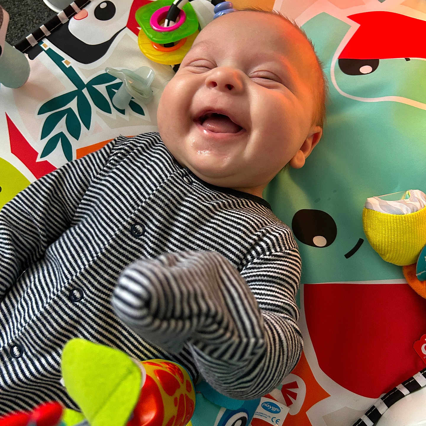 Zayn is registered to the contest to win money with this photo: baby, babylaughing, bodypart, clothing, face, finger, glove, hand, happy, head, homedecor, laughing, newborn, person, photography, portrait, quilt, smile, tape, toy