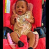 baby, child, car_seat, red, smiling, bib, clothing, infant, happy, portrait, sitting, black_socks, cute, young_child, indoors, seat_belt, person, face, head, expression
