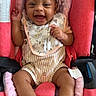 Rhyver joined the competition — help win amazing prizes! baby, child, car_seat, smiling, happy, infant, clothing, bib, socks, seat, cute, portrait, young_child, indoor, person, face, expression, comfort, pink, red