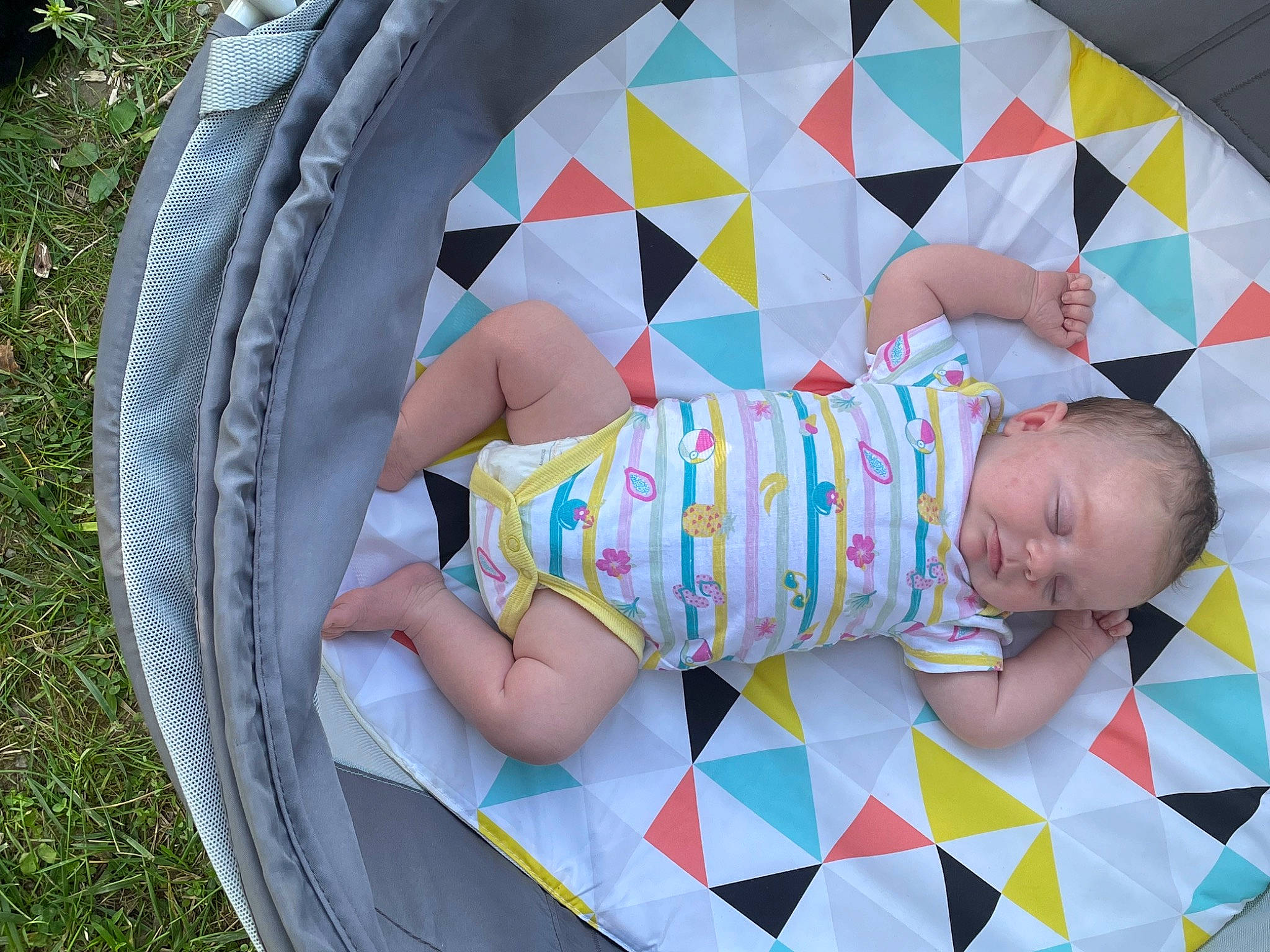 Lilyanna is registered to the contest to win money with this photo: automotive_tire, baby, baby_products, baby_toddler_clothing, child, circle, comfort, facial_expression, fun, grass, leaf, leg, leisure, mammal, pattern, people, person, play, product, t_shirt