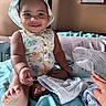 baby, child, smiling, hat, clothing, bed, blanket, blue, hand, foot, cute, indoor, portrait, person, playful, fabric, toddler, happy, animal_print, sitting