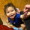 toddler, child, smiling, curly_hair, blue_shirt, socks, wooden_floor, happy, indoor, person, cute, baby, hand, sitting, playful, young_child, portrait, casual_clothing, bright, curious
