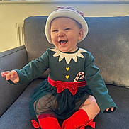 Nova-Mae is registered to the contest to win money with this photo: baby, child, smiling, holiday_outfit, santa_hat, candy_cane, red_socks, green_dress, bow, couch, indoor, window, plants, happy, cute, portrait, toddler, festive, cozy, celebration