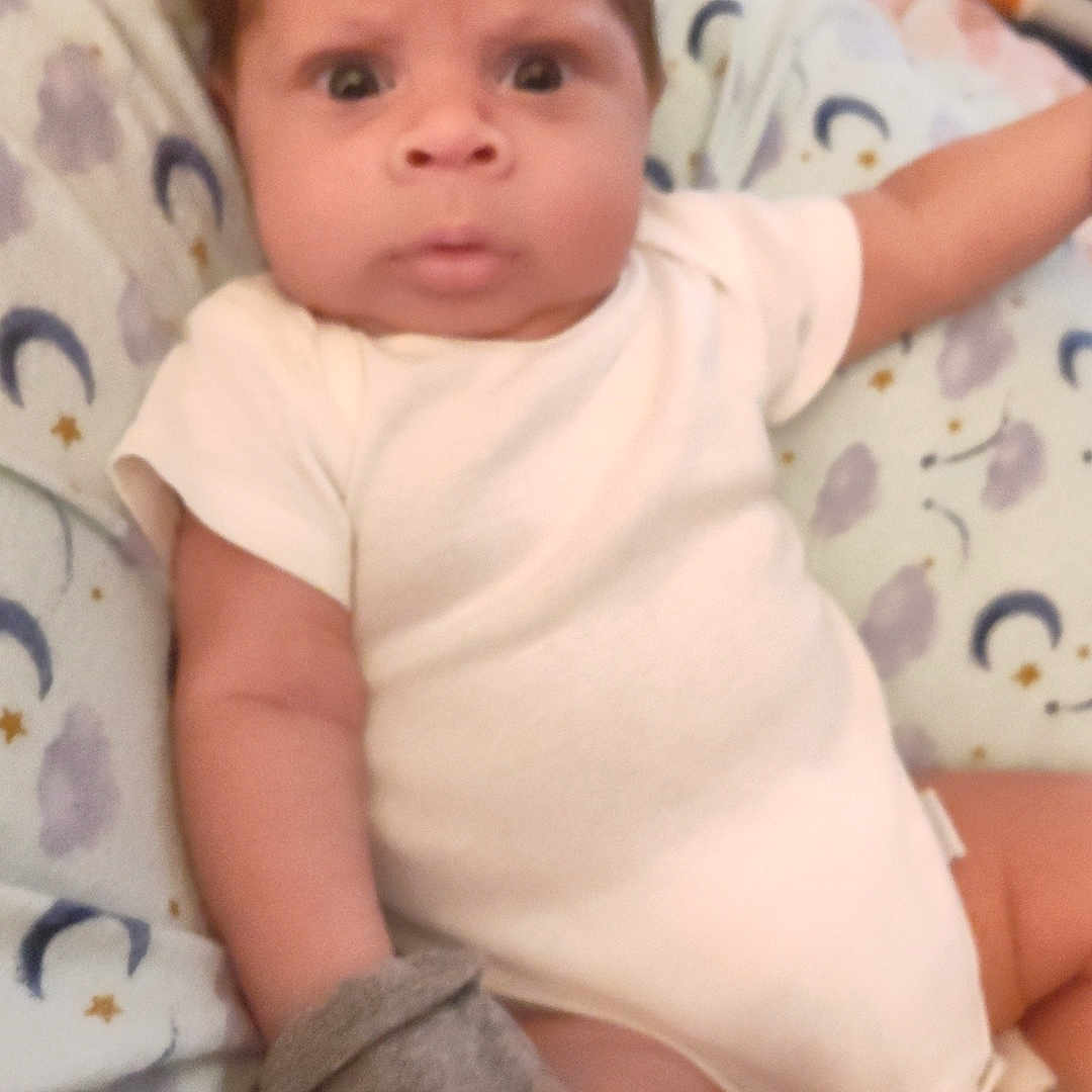 Ja'Cory is registered to the contest to win money with this photo: baby, bed, blanket, child, curious, cute, expression, face, indoor, infant, mitten, newborn, onesie, person, portrait, resting, sleepwear, soft_fabric, wide_eyes, young