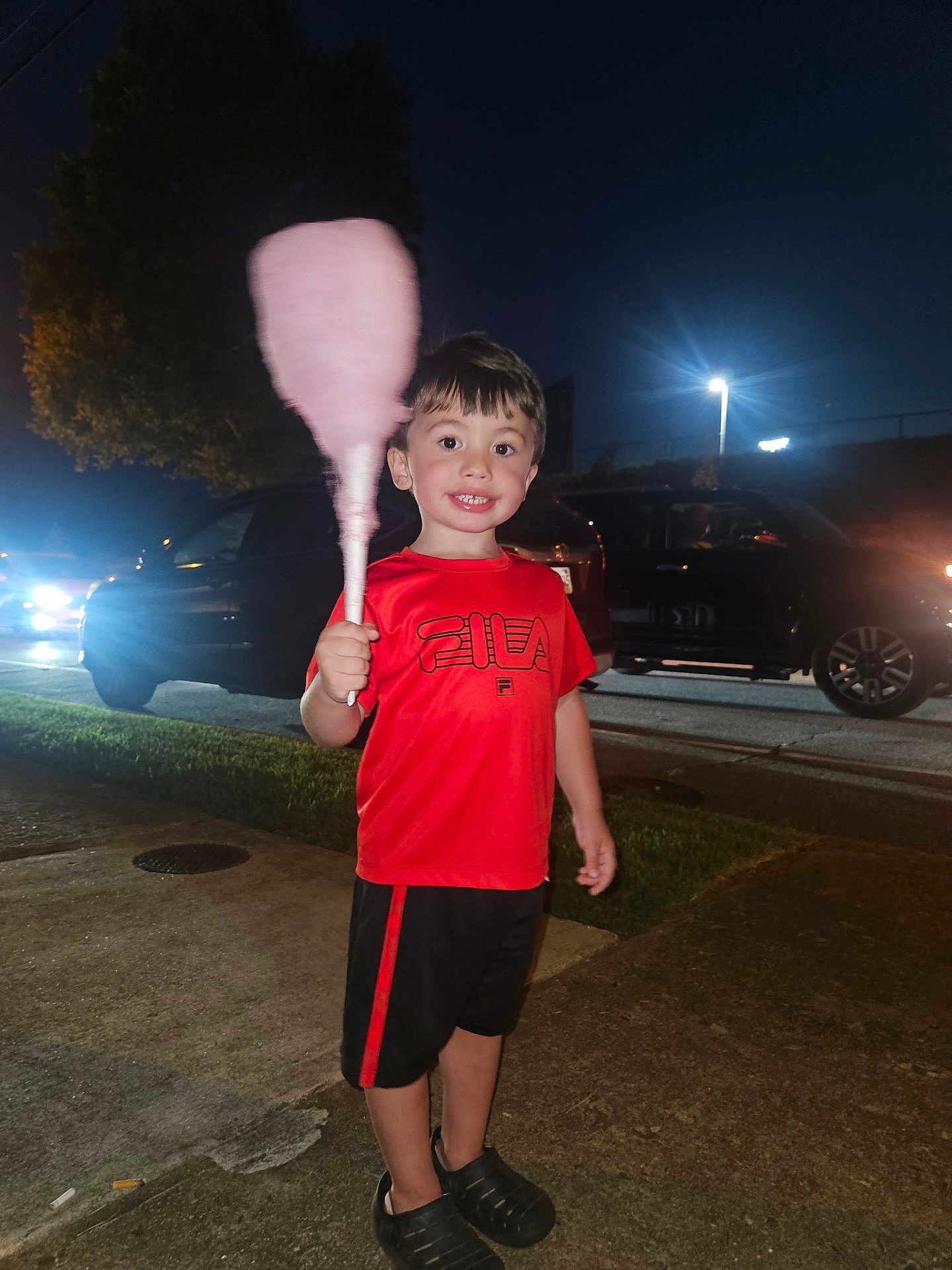 Greyson is registered to the contest to win money with this photo: child, boy, cotton_candy, red_shirt, black_shorts, sidewalk, night, streetlights, cars, grass, smile, short_hair, outdoor, holding, food, happy, casual_clothing, person, recreation, evening