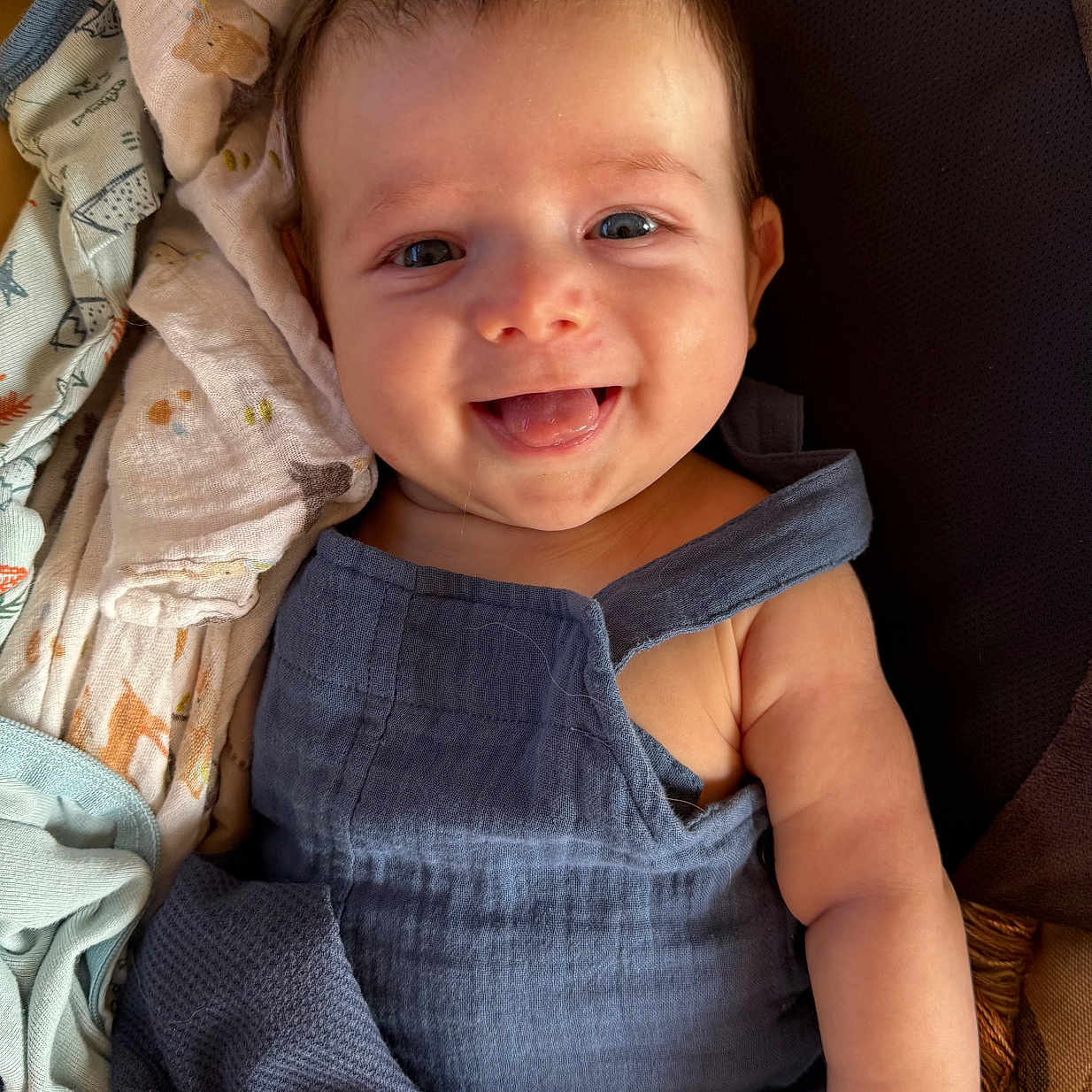 Raine is registered to the contest to win money with this photo: arm, baby, blanket, blue_outfit, child, cozy, cute, fabric, face, hair, hand, happy, indoors, infant, portrait, sitting, skin, smile, soft, tongue_out