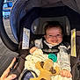 baby, car_seat, smiling, toy, plush_dog, pacifier, hand, blanket, clothing, infant, child, seatbelt, indoor, person, cute, happy, face, portrait, baby_girl, baby_boy