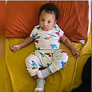Mellow is registered to the contest to win money with this photo: baby, brown, casual, child, clothing, couch, cute, home, indoor, looking_at_camera, mickey_mouse, pajamas, person, pillow, portrait, relaxing, seated, socks, toddler, yellow