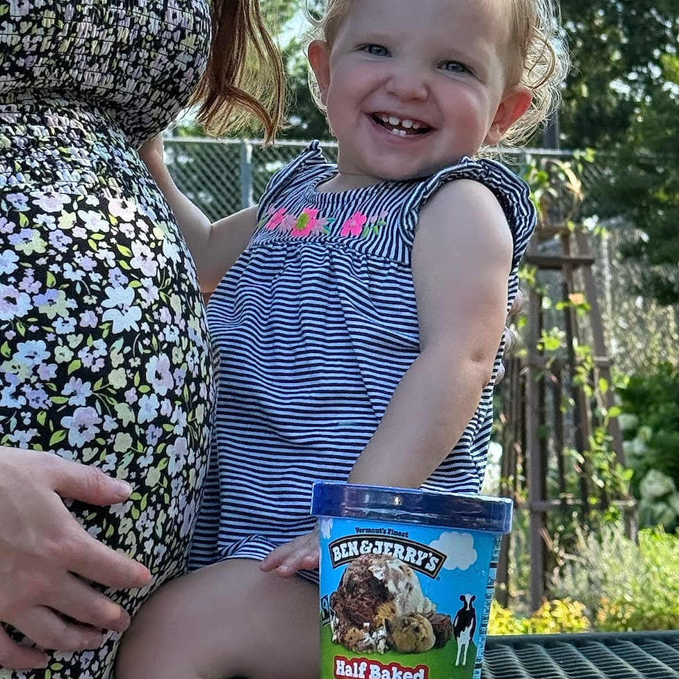 Azona is registered to the contest to win money with this photo: ben_and_jerrys, blue_sky, child, cute, fence, floral_dress, food_container, garden, hand, happy, ice_cream, nature, outdoor, person, picnic_table, pregnant_woman, smiling, striped_dress, sunlight, toddler