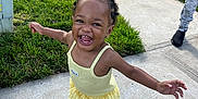 Aaliyah is registered to the contest to win money with this photo: casual_wear, child, concrete, earrings, footwear, grass, greenery, hair_buns, happy, joyful, outdoor, person, playful, running, sidewalk, smiling, sunny_day, toddler, yellow_clothing, young_child