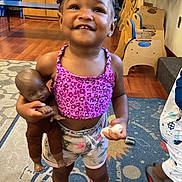 Aaliyah joined the competition — help win amazing prizes! braided_hair, carpet, child, cute, doll, floral_shorts, footwear, furniture, girl, happy, indoor, person, pink_shoes, playroom, portrait, purple_top, smiling, toddler, toy, wooden_floor