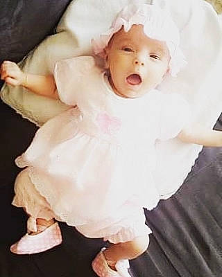 Naëlle a rejoint le concours — aidez-le/la à gagner de superbes lots ! baby, baby_laughing, child, child_model, costume, dress, person, pink, product, skin, sleeve, smile, toddler