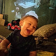 Westley joined the competition — help win amazing prizes! child, toddler, laughing, indoor, toy_car, pillow, blanket, furniture, person, happy, home, smile, clothing, face, living_room, blur, cozy, cute, young_child, play