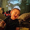 child, toddler, laughing, indoor, toy_car, pillow, blanket, furniture, person, happy, home, smile, clothing, face, living_room, blur, cozy, cute, young_child, play