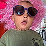 Kaleb is registered to the contest to win money with this photo: toddler, child, sunglasses, pink_wig, curly_hair, green_shirt, indoor, portrait, person, funny_expression, casual_clothing, headwear, cute, young_child, face, fashion_accessory, hair, eyewear, closeup, humor