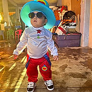 Kaleb joined the competition — help win amazing prizes! child, costume, hat, sunglasses, indoor, floor, clothing, person, standing, shoes, red_pants, white_shirt, colorful, playful, casual, young_child, portrait, toy_room, light, shadow