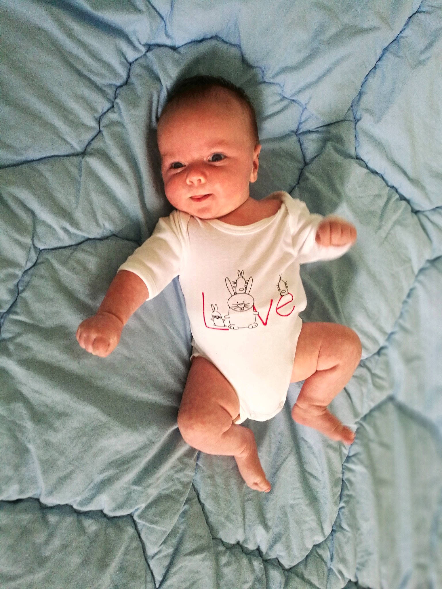 Victor participe au concours pour gagner de l'argent avec cette photo : arm, baby, baby_products, baby_toddler_clothing, bedding, blanket, child, fun, gesture, hand, happy, head, linens, person, product, skin, sleeve, smile, t_shirt, textile