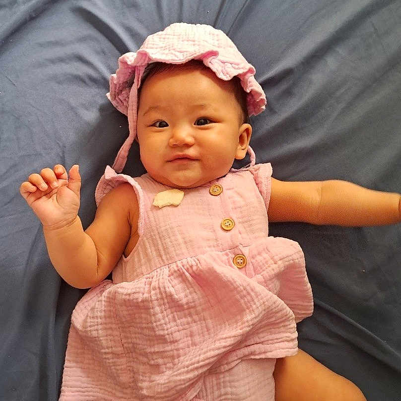 Abigail joined the competition — help win amazing prizes! baby, bodypart, bonnet, bread, cap, clothing, dress, face, finger, food, hand, hat, head, newborn, pants, person, photography, portrait, quilt, sitting