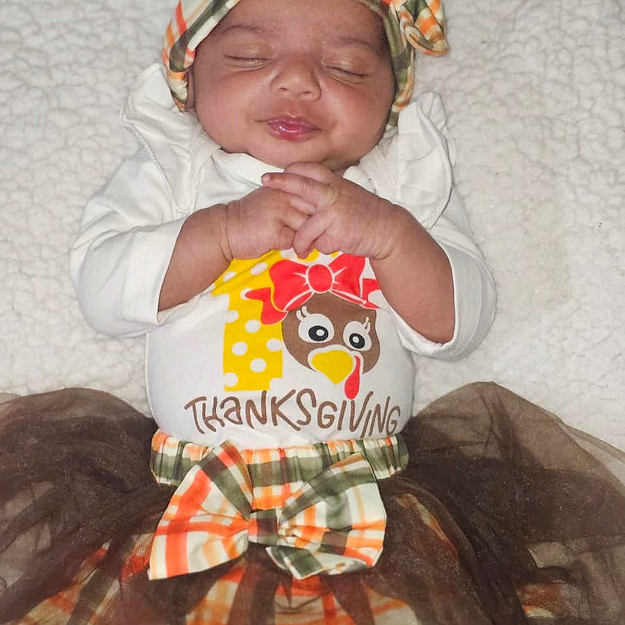 Amaya joined the competition — help win amazing prizes! baby, blanket, child, cozy, cute, festive, hands_clasped, happy, headband, holiday, indoor, infant, plaid, portrait, skirt, sleeping, smiling, thanksgiving, toddler, white_clothing