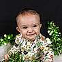 baby, infant, smiling, portrait, face, eyes, onesie, clover_pattern, rainbow, stars, green_tinsel, tinsel, holiday_decor, cute, cheerful, studio_background, closeup, sitting, hands, sparkle