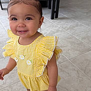 Jazmine is registered to the contest to win money with this photo: toddler, child, smiling, yellow_dress, sandals, hair_clips, indoor, floor_tiles, kitchen, table, chairs, cute, happy, person, fashion, young_child, standing, accessories, playful, portrait