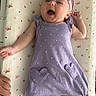 baby, infant, smiling, purple_outfit, headband, heart_pockets, lying_down, butterfly_pattern, bed_sheet, cute, happy, child, one_person, indoor, closeup, skin, arm, hand, foot, baby_clothes