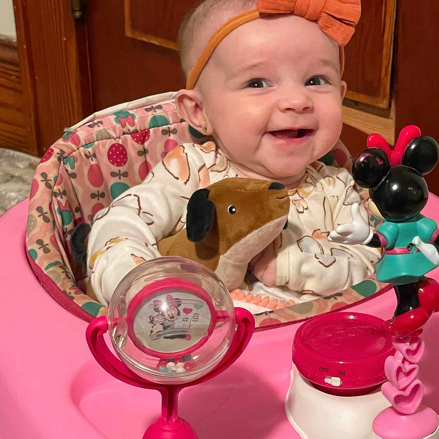Zayley joined the competition — help win amazing prizes! baby, baby_walker, bow, child, clothing, cute, dog_toy, face, happy, headband, indoor, infant, minnie_mouse, person, pink, plush_toy, sitting, smiling, toy, wooden_cabinet