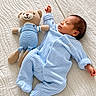 baby, newborn, sleeping, teddy_bear, stuffed_animal, blue_outfit, romper, bed, quilt, bedroom, portrait, infant, peaceful, cozy, indoors, soft_lighting, matching_outfits, lying_down, nursery, cuddly